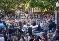 A crowd of people dance in front of a stage where a live band is playing