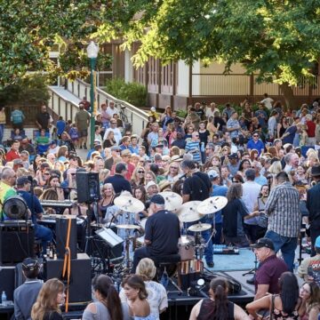 A crowd of people dance in front of a stage where a live band is playing