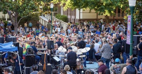 A crowd of people dance in front of a stage where a live band is playing