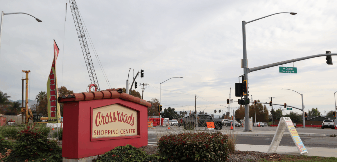A shopping center sign in the foreground, with a construction crane in the background