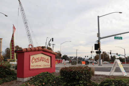 A shopping center sign in the foreground, with a construction crane in the background