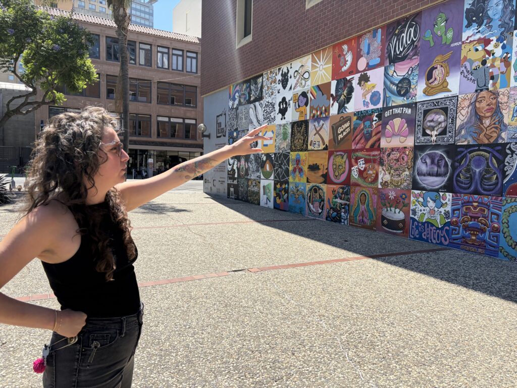 A woman stands pointing to a mural in San Jose, California