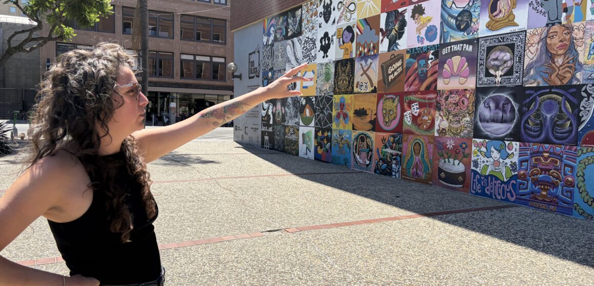 A woman stands pointing to a mural in San Jose, California