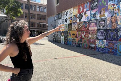 A woman stands pointing to a mural in San Jose, California