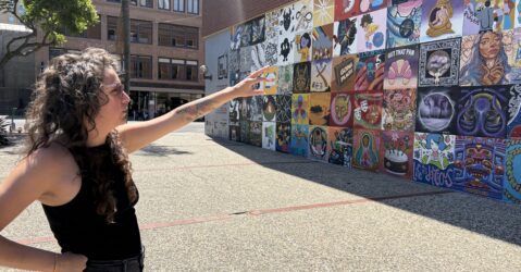 A woman stands pointing to a mural in San Jose, California