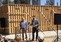 Two men speak to an audience at a construction site in Santa Clara, California