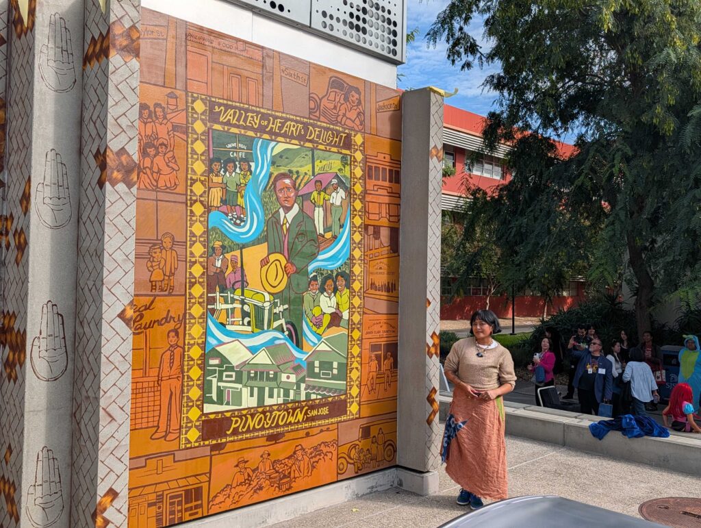 A woman standing next to a mural on a college campus in San Jose, California